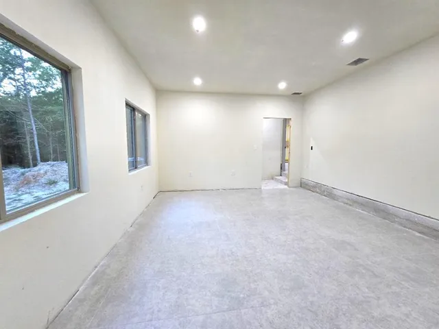 an empty room with windows and view of hallway
