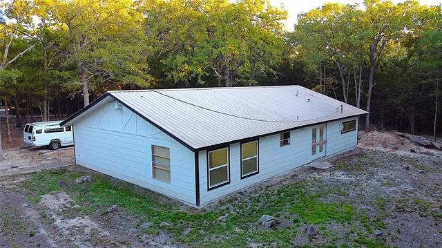 a aerial view of a house with yard and trees in the background
