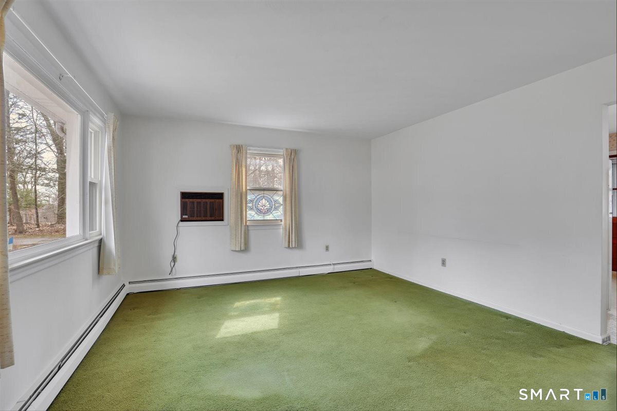 47 Park Road Colchester, CT 06415 - Photo 6 of 31 Sun-lit living area with a unique custom stained glass window and built-in wall AC for seasonal comfort.