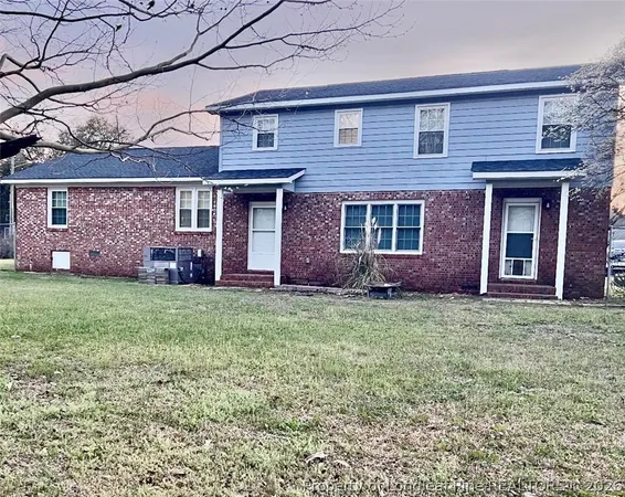 a view of a brick house with a yard and plants