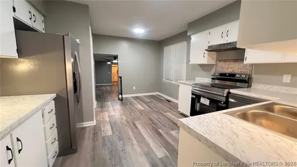 a kitchen with granite countertop a refrigerator stove and sink