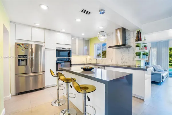 a kitchen with stainless steel appliances granite countertop a sink a stove a refrigerator and a refrigerator with wooden floor