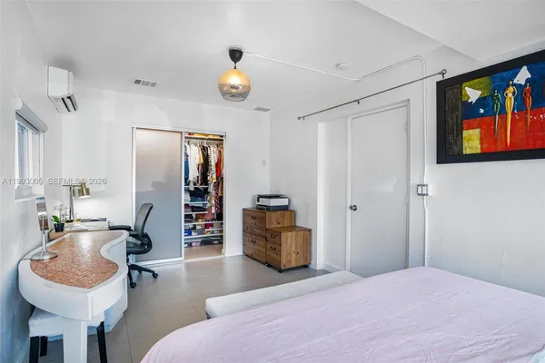 a bedroom with a bed and a flat tv screen on dresser