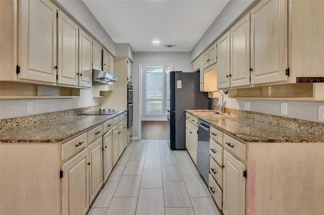 a kitchen with granite countertop a sink stove refrigerator and cabinets