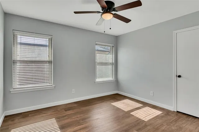 a view of empty room with wooden floor and fan