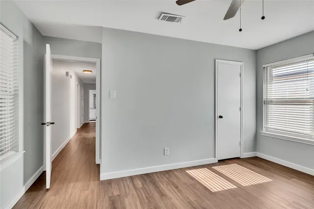a view of an empty room with wooden floor and a window