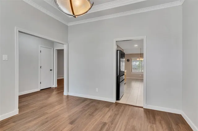 a view of an empty room with wooden floor and a mirror