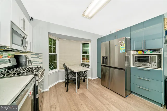 a kitchen with a refrigerator a stove top oven a sink dishwasher and dining table with wooden floor