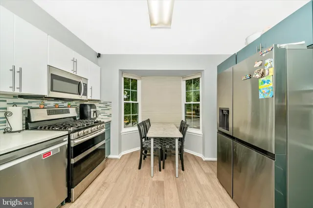 a kitchen with granite countertop a refrigerator a stove a sink a dining table and chairs with wooden floor