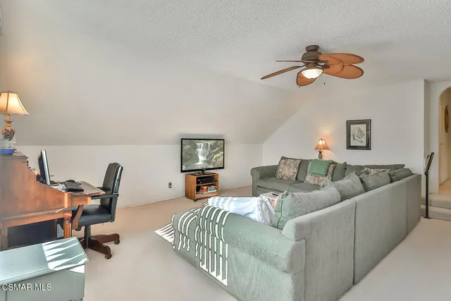 a living room with furniture a flat screen tv and a large window
