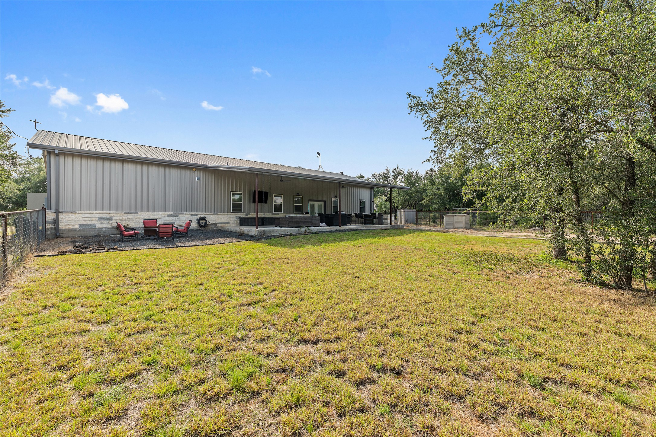 764 Stubbs Road Johnson City, TX 78636 - Photo 29 of 29 A spacious backyard with mature trees complements the modern structure's large covered patio.