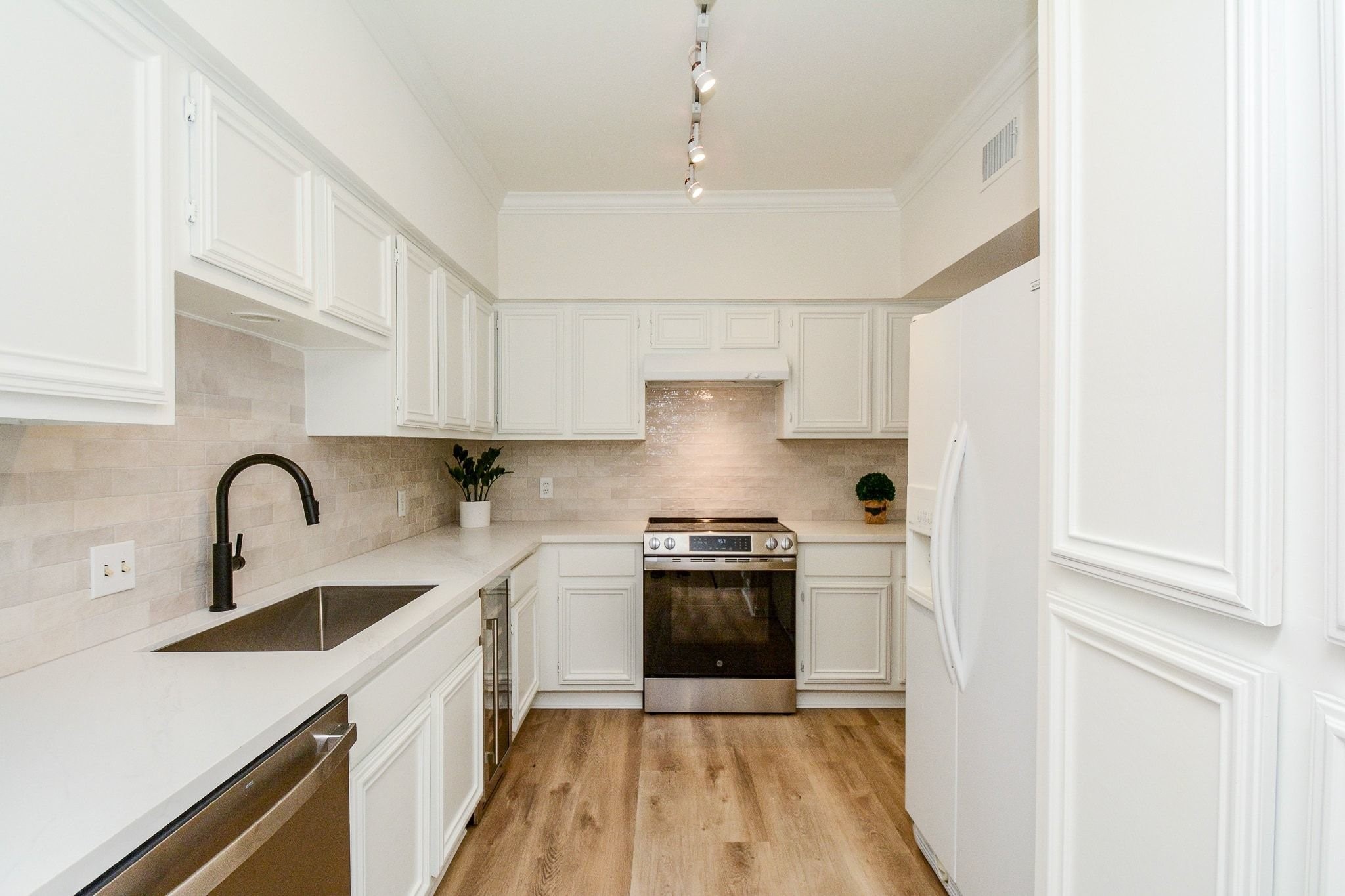 820 Harold Street Houston, TX 77006 - Photo 6 of 33 Updated white cabinetry, quartz countertops, a neutral tile backsplash, and stainless appliances make this kitchen both functional and fresh.
