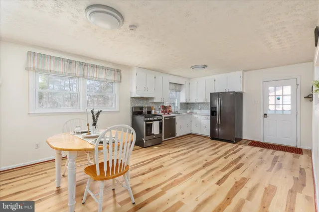 a kitchen with granite countertop a refrigerator a stove a dining table and chairs