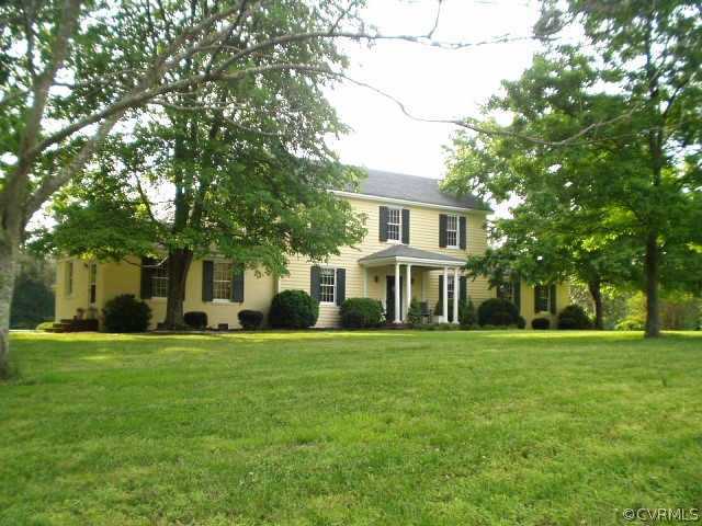 front view of a brick house with a big yard and large trees