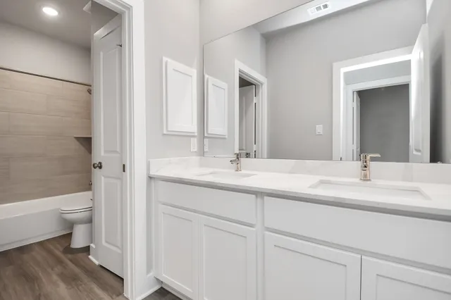a bathroom with a double vanity sink toilet and shower
