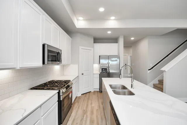 a kitchen with stainless steel appliances kitchen island a stove a sink and a refrigerator