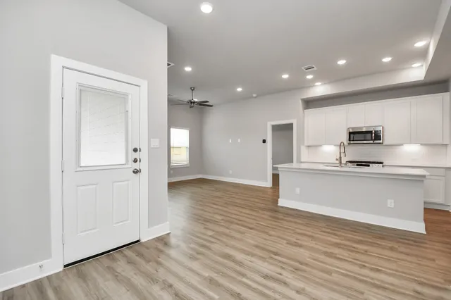 a large kitchen with stainless steel appliances a large counter top and wooden floors