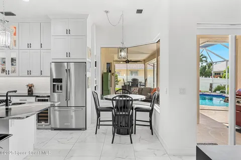 a kitchen with stainless steel appliances a refrigerator a stove a dining table and chairs