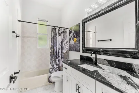 a bathroom with a granite countertop sink a toilet and shower