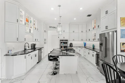 a kitchen with stainless steel appliances kitchen island granite countertop a sink and a refrigerator