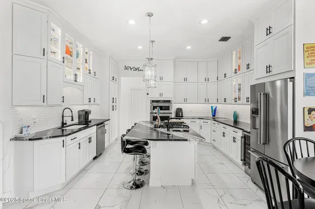 a kitchen with stainless steel appliances kitchen island granite countertop a sink and a refrigerator
