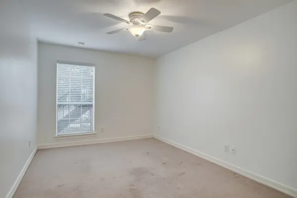 an empty room with a window and a fan