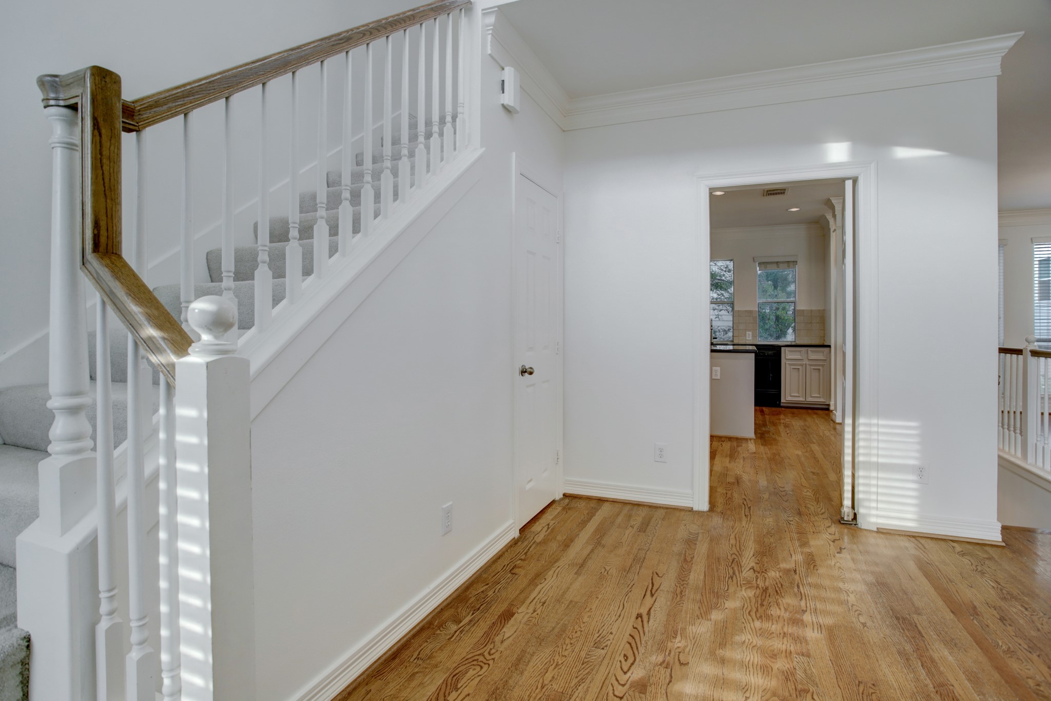 2205 Commonwealth Street Houston, TX 77006 - Photo 3 of 22 Entry hall with high ceilings, wood floors. Stairway leads up to primary bedroom suite and secondary bedroom. Door under the stairs opens to half bathroom.