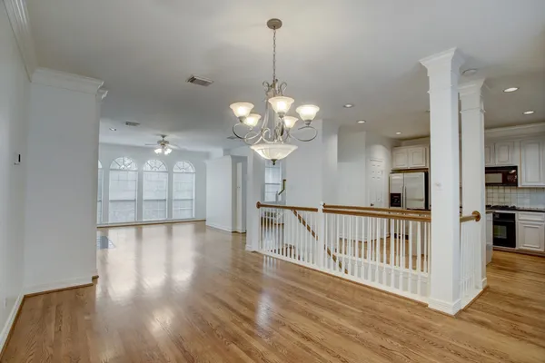a view of a hallway with wooden floor and a chandelier