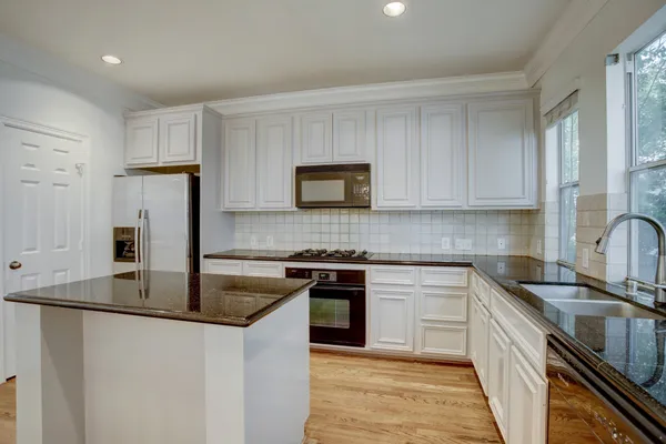a kitchen with granite countertop a sink stove and refrigerator