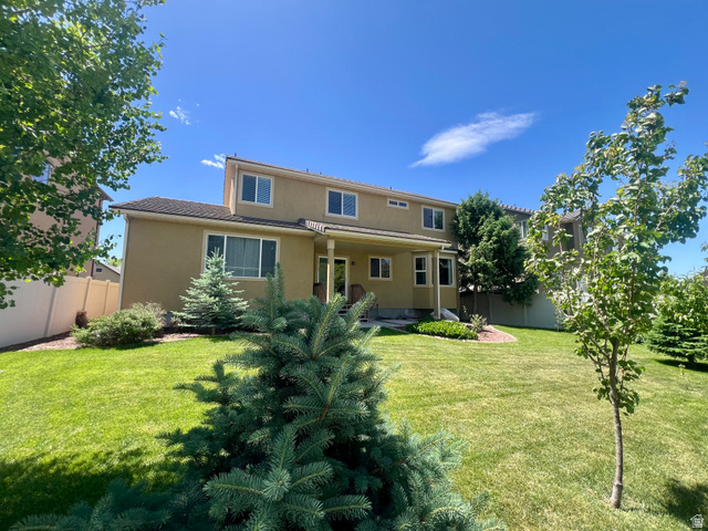 369 Culross Circle Tooele, UT 84074 - Photo 46 of 54 Expansive lawn featuring mature trees and shrubbery, a covered patio, and a two-story stucco exterior