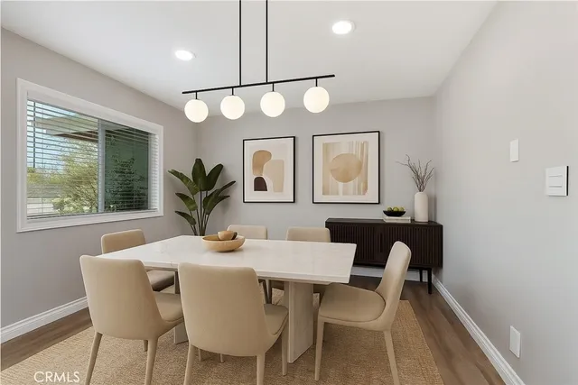a dining room with wooden floor a chandelier fan a wooden table and chairs