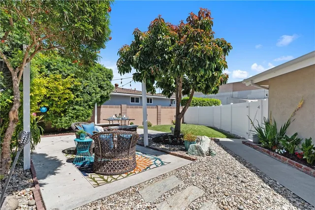 a view of a backyard with table and chairs potted plants and large tree