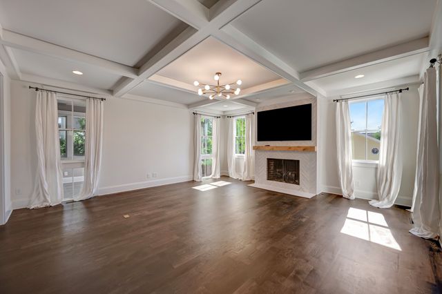 an empty room with wooden floor a fireplace and a large window