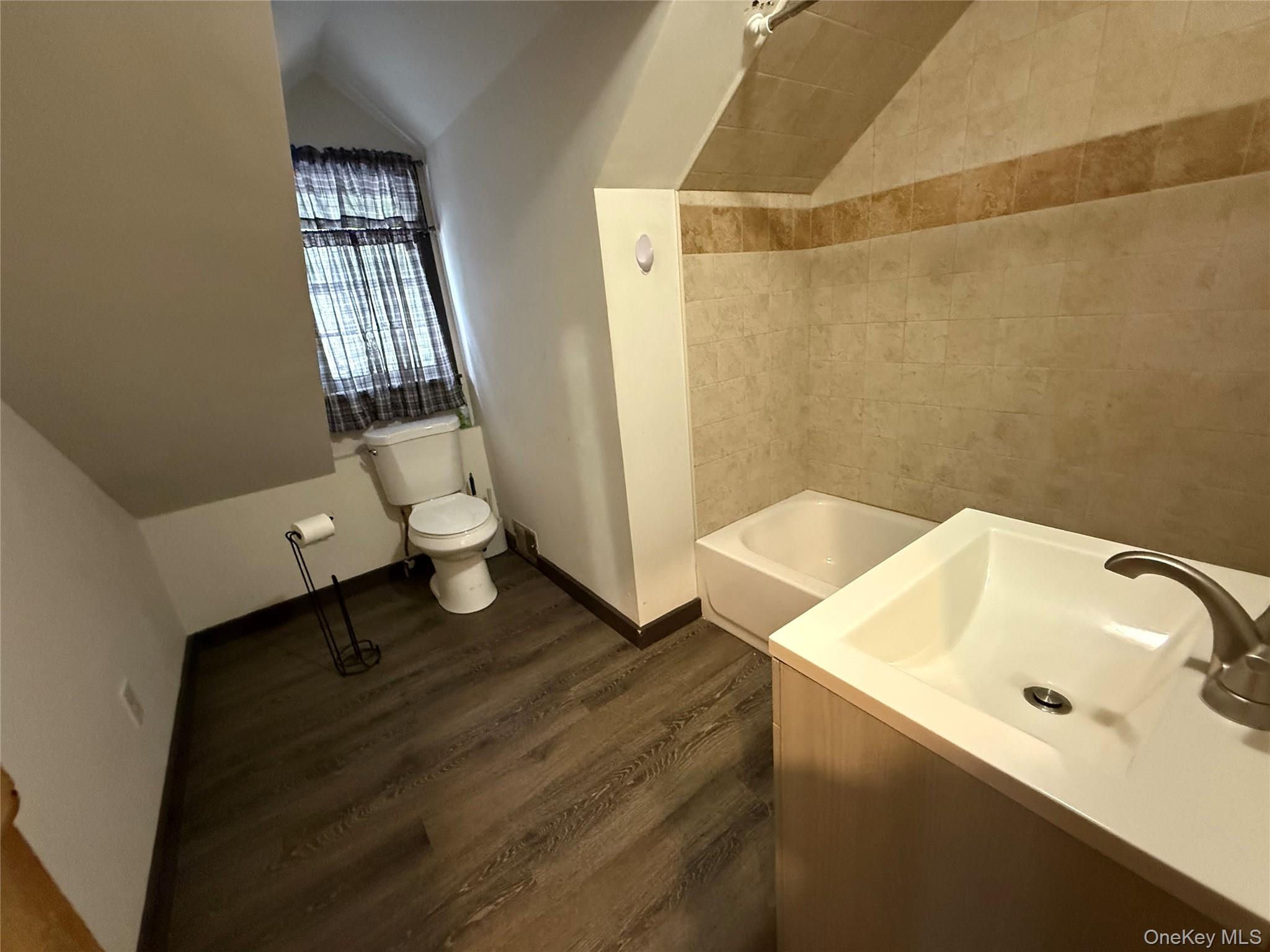241 White Bridge Road Middletown, NY 10940 - Photo 24 of 29 Bathroom featuring vaulted ceiling, dark wood-type flooring, vanity, and bathtub / shower combination