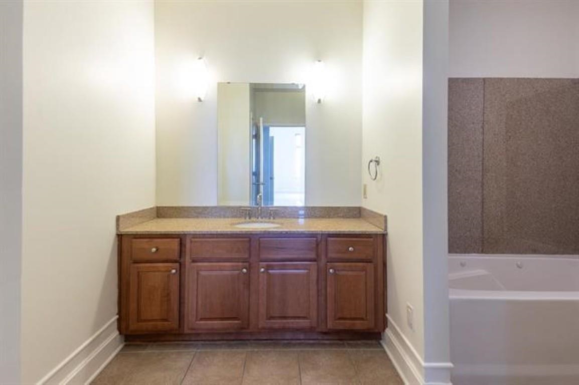 648 Riverside Drive, Unit 319 Memphis, TN 38103 - Photo 11 of 19 a bathroom with a granite countertop sink a mirror and a bathtub