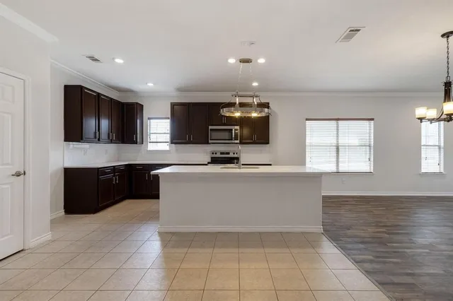 a large white kitchen with kitchen island granite countertop a sink a stove a microwave a counter top and cabinets
