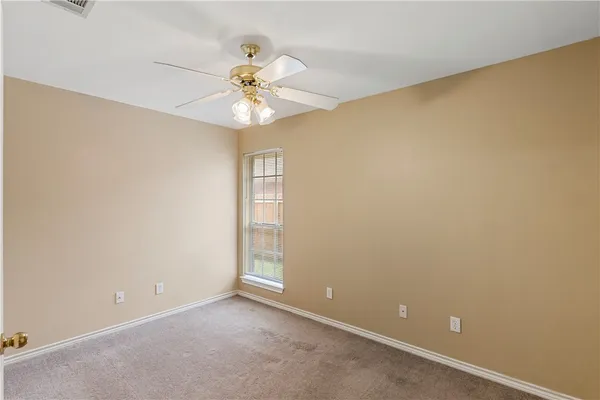 an empty room with a window and a fan