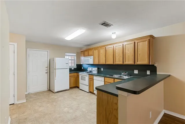 a kitchen with a refrigerator a stove a sink dishwasher and wooden cabinets
