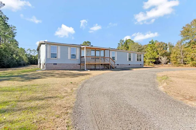 a view of a house with a big yard and large trees