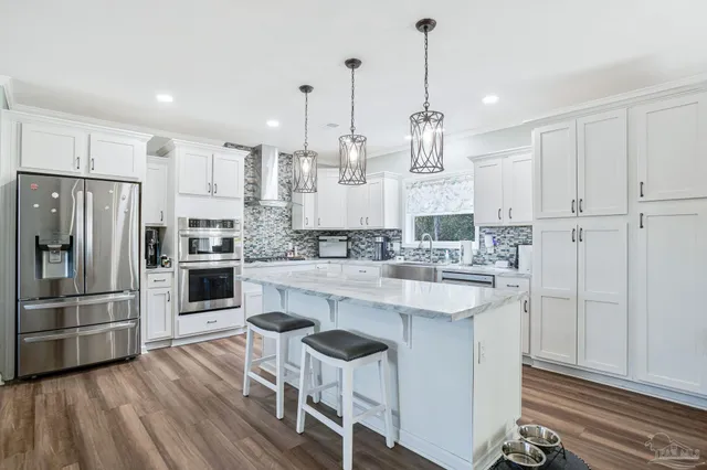 a large kitchen with kitchen island white cabinets and stainless steel appliances