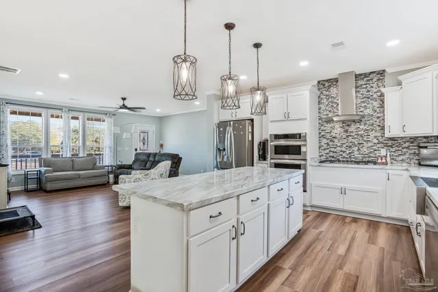 a large kitchen with kitchen island a large counter space a sink appliances and living room view