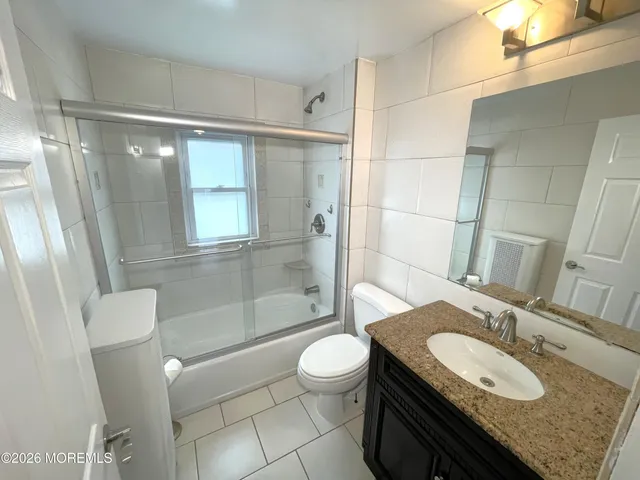 a bathroom with a granite countertop sink toilet a mirror and shower