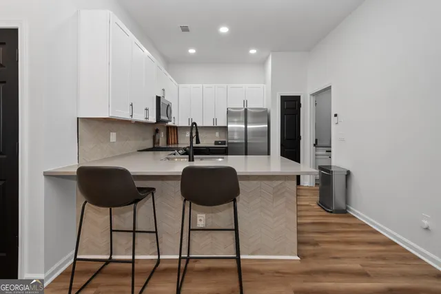a kitchen with stainless steel appliances a dining table chairs and a refrigerator
