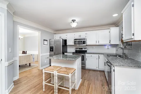 a kitchen with stainless steel appliances granite countertop a white cabinets and wooden floor