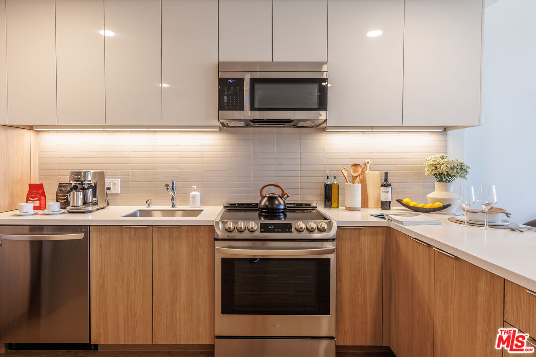 11750 Wilshire Boulevard, Unit 2404 Los Angeles, CA 90025 - Photo 9 of 38 a kitchen with stainless steel appliances granite countertop a sink a stove a microwave oven and cabinets