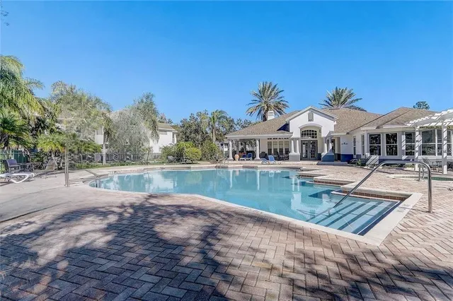 a view of house with swimming pool and a yard