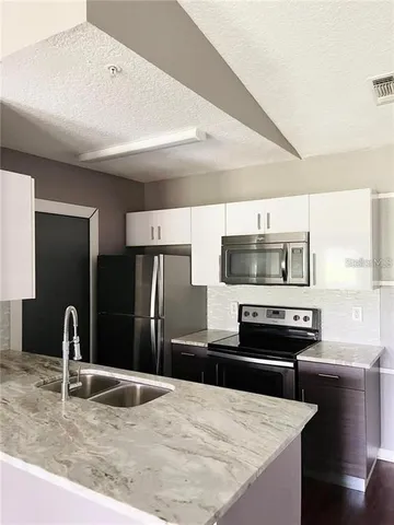 a kitchen with stainless steel appliances kitchen island granite countertop a refrigerator and a sink