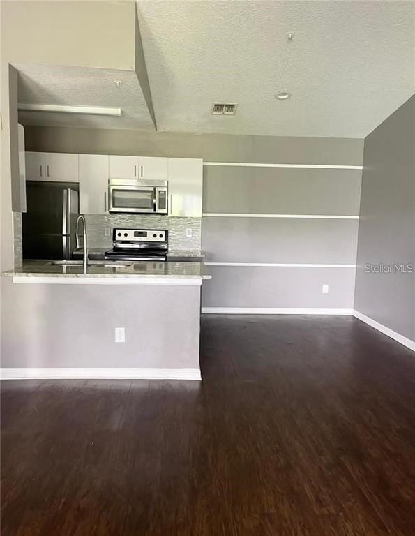 4348 South Kirkman Road, Unit 806 Orlando, FL 32811 - Photo 9 of 29 a view of kitchen with stainless steel appliances a sink dishwasher stove refrigerator and microwave with wooden floor