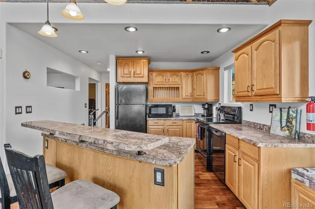 a kitchen with stainless steel appliances granite countertop a sink a stove a refrigerator cabinets and chairs