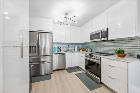 a kitchen with stainless steel appliances kitchen island a refrigerator sink and cabinets